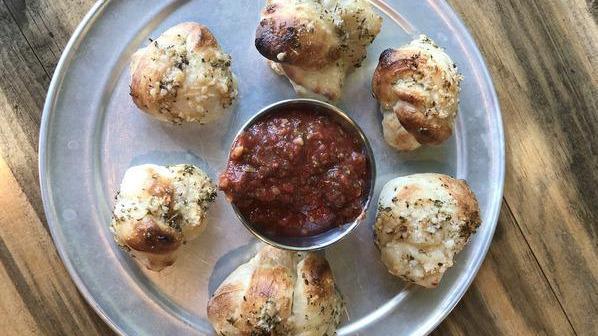 Garlic Knots · Hand crafted garlic knots smothered in garlic oil and finished with fresh garlic, herbs and parmesan cheese.
