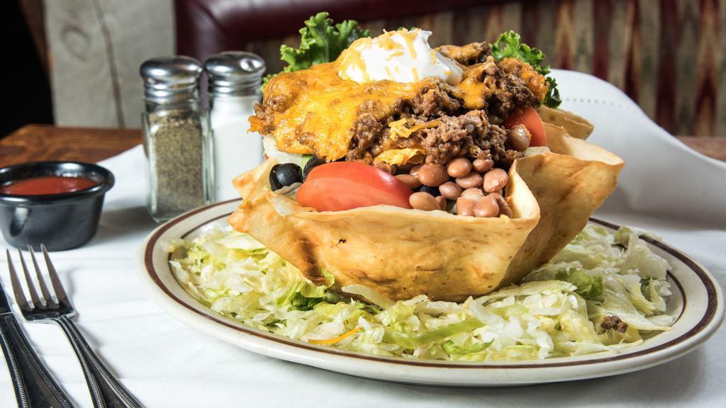Taco Salad · Beef or chicken and whole beans on salad greens, served in a crisp tortilla shell, and garnished with avocado slices, sour cream, black olives, and shredded cheese.