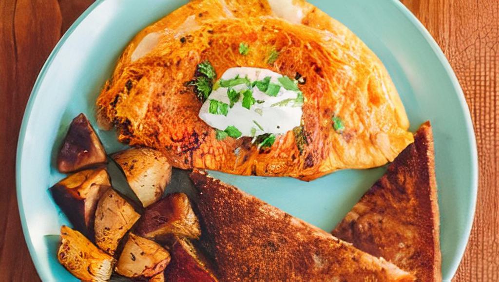 Chorizo Omelette · Three egg omelette with chorizo, onions, tomatoes, five cheese blend, topped off with cilantro and crema on top. Served with your choice of toast, and roasted potatoes or fruit.