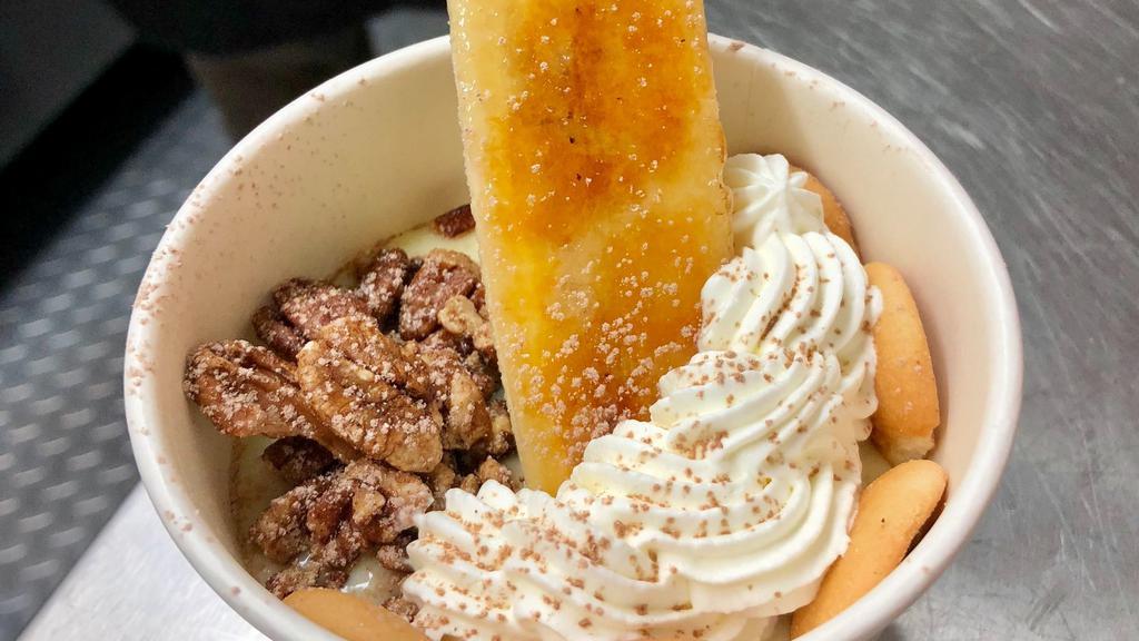 Banana Pudding · Scratch-made banana pudding topped with candied pecans, vanilla bean whipped cream, mini Nilla wafers, cocoa sugar-dusted, and brûléed banana.