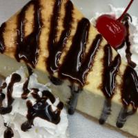 Cheesecake · New York cheesecake topped with chocolate drizzle whipped cream and cherry on side.