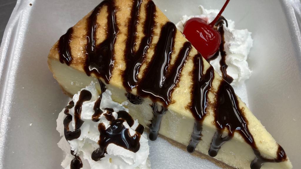Cheesecake · New York cheesecake topped with chocolate drizzle whipped cream and cherry on side.