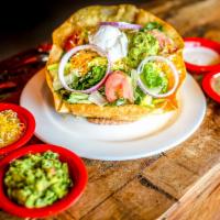 Tostada Salad · Large flour tortilla fried into a tostada shell seated on refried beans. Onto crispy greens,...