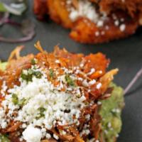 Los Maduros Con Carne · Two fried ripe plantains topped with cochinita, guacamole, and cotija cheese. Drizzled with ...