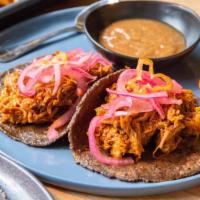 2 Cochinita Tacos · Slow-roasted pork in achiote and banana leaf, served on three sisters corn tortilla with hab...