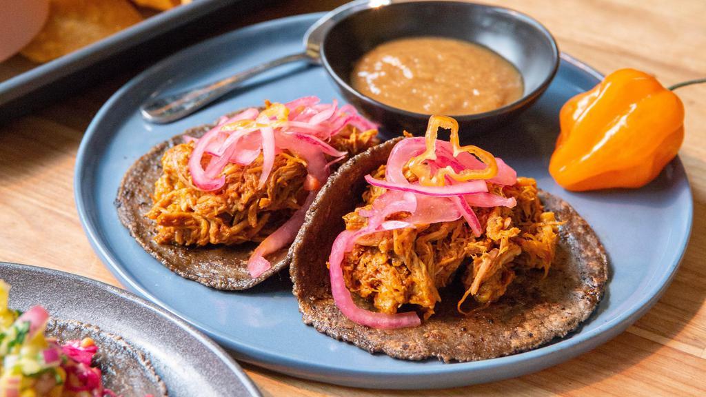 2 Cochinita Tacos · Slow-roasted pork in achiote and banana leaf, served on three sisters corn tortilla with habanero pickled red onions.