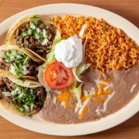 39 Taco Plate · Three tacos (with onions, cilantro, green salsa), rice, beans (cheese on top), lettuce, toma...