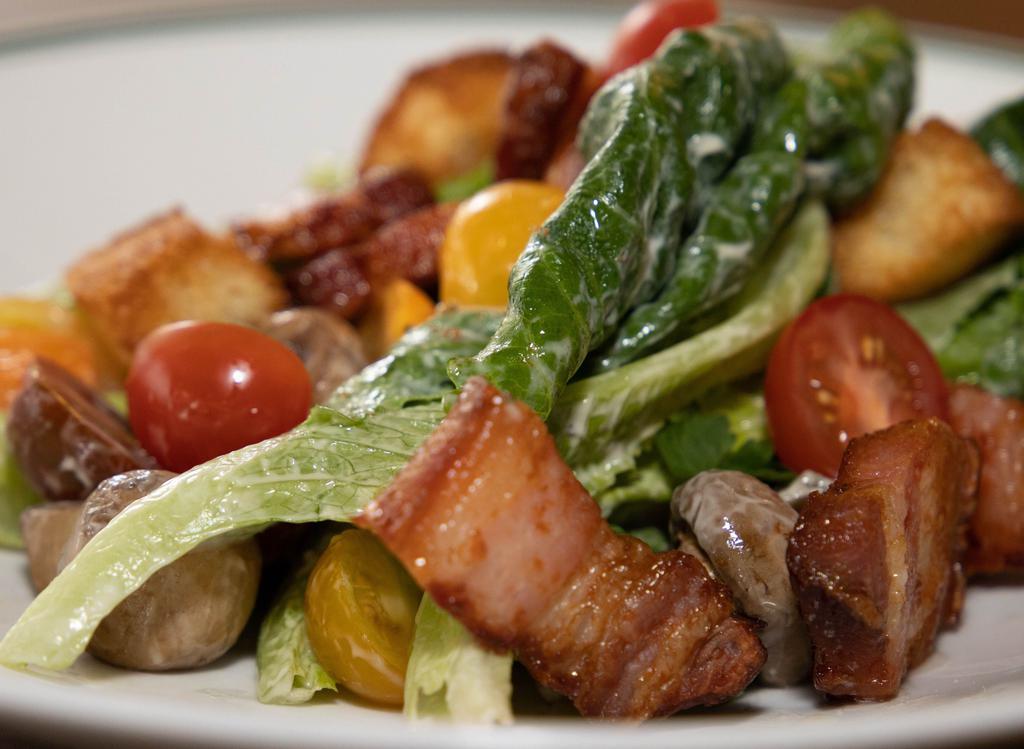 Wollensky Salad · Romaine lettuce, heirloom tomatoes, potato croutons, bacon lardons, marinated mushrooms, and Dijon vinaigrette.