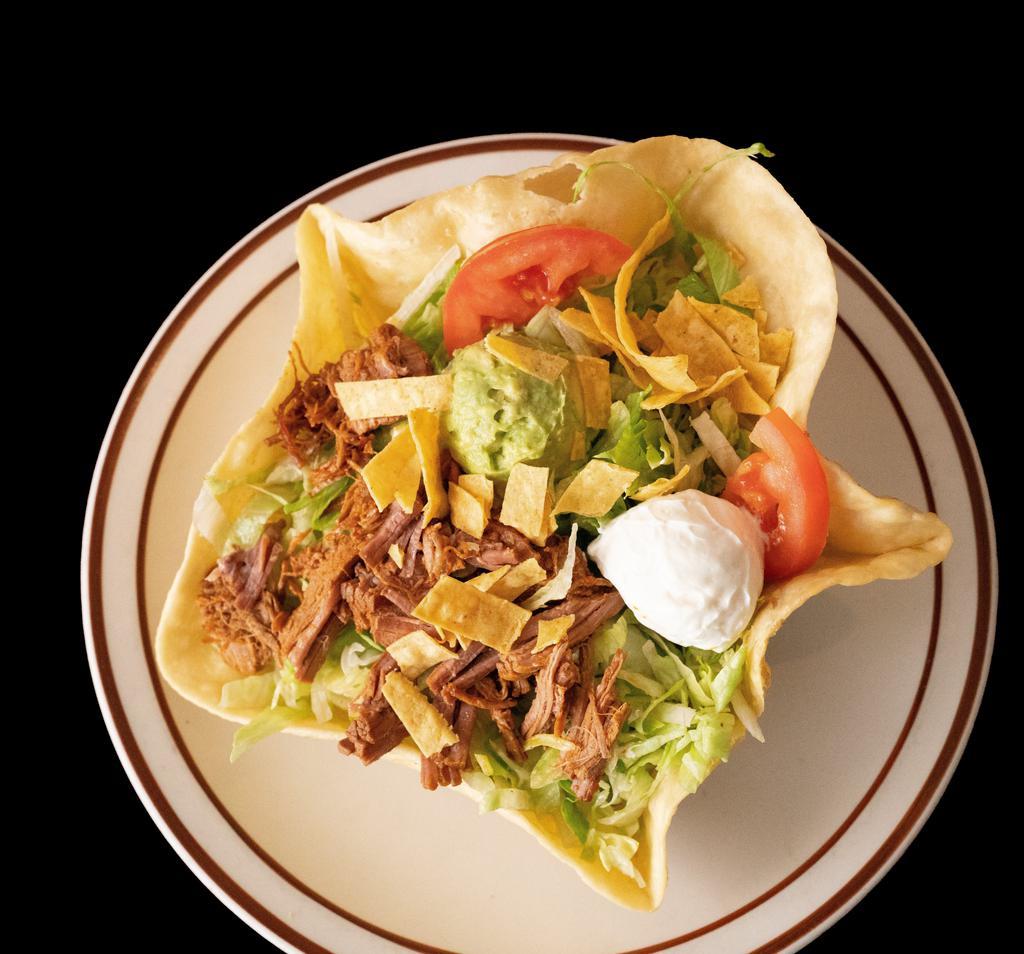 Taco Salad · A crispy flour tortilla shell topped with beans, your choice of meat, lettuce, sour cream, guacamole, cheddar cheese, tomatoes, and crispy corn tortilla chips.