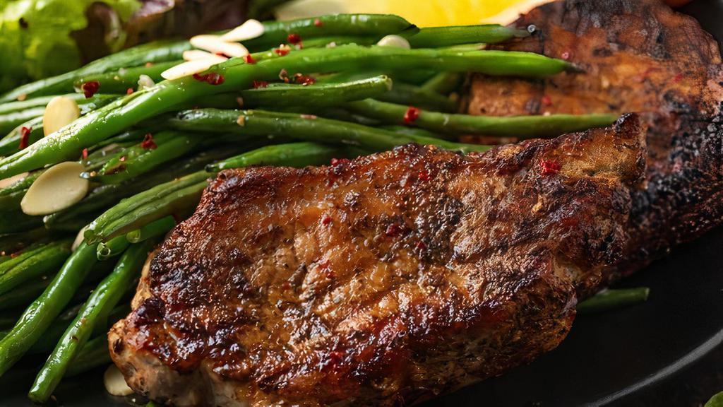 Pork Chops · Grilled marinated pork chops served with steamed rice and seasoned green beans topped with pork sausage bits.