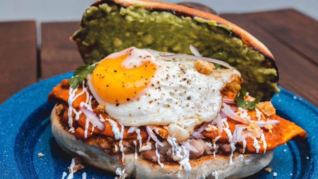 Chilaquil Torta · Macrina ciabatta bun, beans, eggs, chilaquiles with its toppings(sour cream, cotija cheese, cilantro, avocado, radish, and red pickled onion.