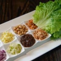 Meang Kum · Thai pepper and lettuce leaf, folding it over a mix of ingredients of shallots, peanuts, toa...