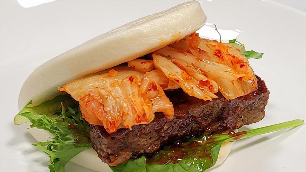 Kimchi Imposstor Bao · Impossible soy-based vegetarian protein with Korean-style spicy sauce, kimchi, and spring salad on a fluffy steamed bun. (Palm-sized ~4inches diameter taco shell style bao.)