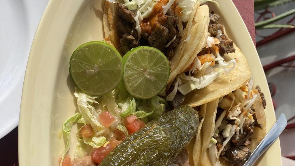 Tacos De Carne Asada · Three soft shell tacos with seasoned chunks of beef steak, served with onions, green peppers and lettuce. Garnished with guacamole and sour cream.