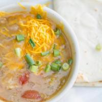 Pork Green Chili · Topped with cheese and served with a tortilla.