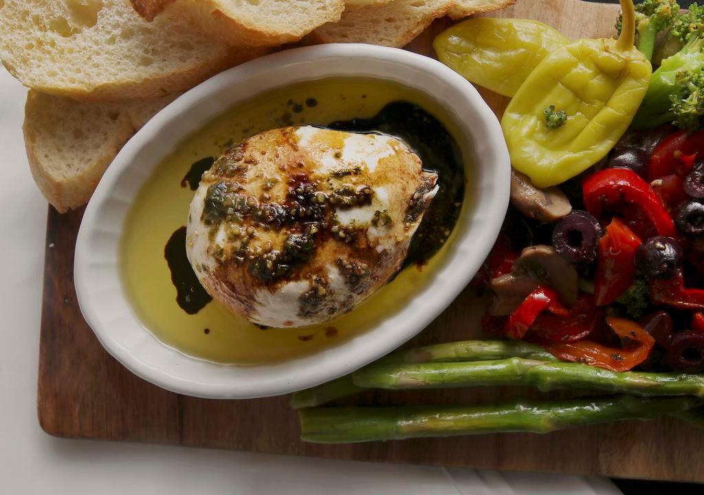 Burrata Cheese Tuscany (Serves 2) · Gluten-free. Mozzarella ball stuffed with ricotta roasted garlic, arugula, roasted red peppers, cherry tomato. Topped with EVOO and a balsamic glaze drizzle. Served with toasted baguettes.