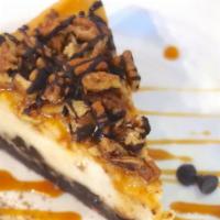 Slice Of Turtle Cheesecake · Chocolate cookie crust, vanilla cheesecake, caramel, chocolate ganache & toasted pecans *con...