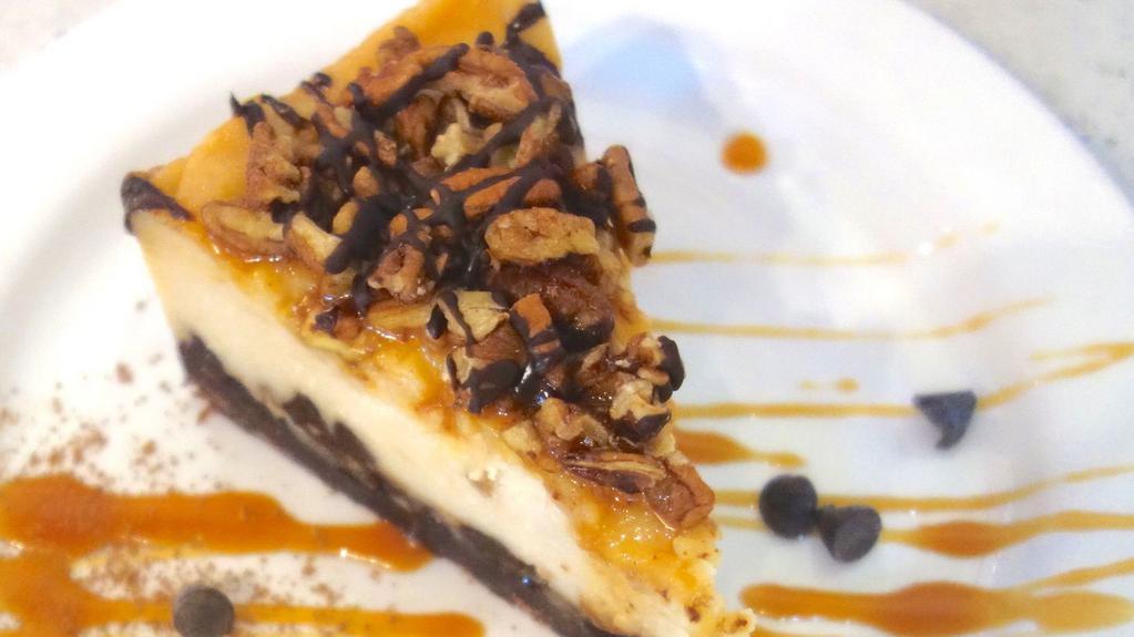 Slice Of Turtle Cheesecake · Chocolate cookie crust, vanilla cheesecake, caramel, chocolate ganache & toasted pecans *contains pecans, coconut & soy