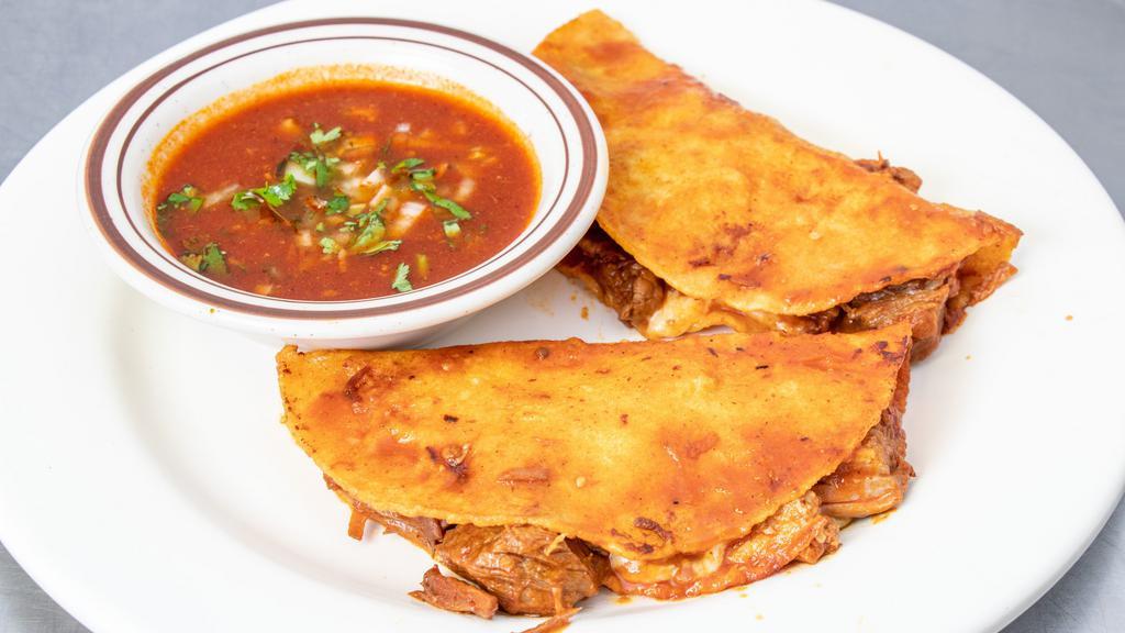 Quesabirria · Two corn tortillas grilled with red non- spicy salsa filled with shredded beef and cheese. Served with a side of consume.