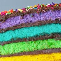 Rainbow Fudge Cake Slice · Six layers of rainbow-colored vanilla cake filled and iced with chocolate fudge frosting, co...