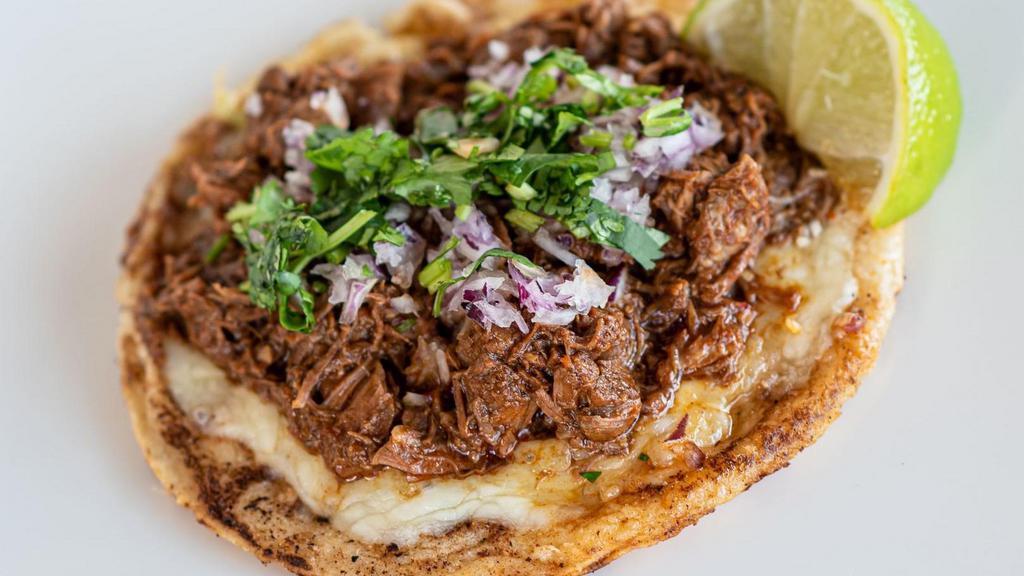 Birria Gordita · Handmade corn tortilla topped with Monterey Jack cheese, shredded beef, diced red onion and cilantro.