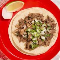 Carnitas Taco · Braised pork topped with cilantro and chopped onion on a soft corn tortilla.