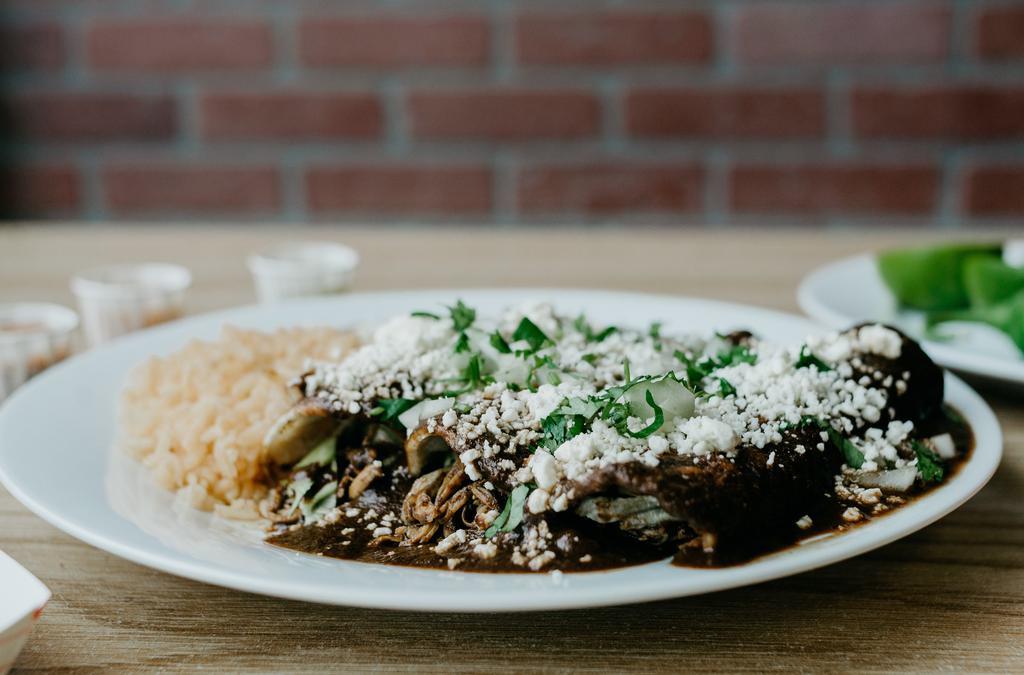 Enchiladas De Mole · Three chicken enchiladas topped with mole sauce, cilantro, onions, and queso fresco,  served with rice and beans.