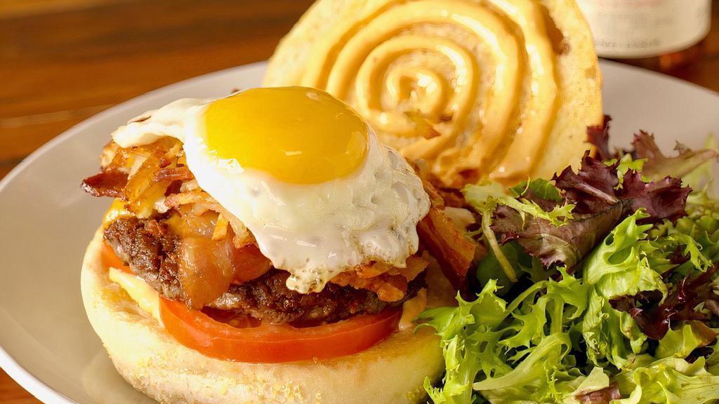 Le Breakfast Burger · Juicy burger with crispy hash browns, grilled local tomato, creamy cheddar cheese, crisp bacon, sriracha aioli and a sunny side farm egg on top, served on grilled La Baguette Bakery rolls