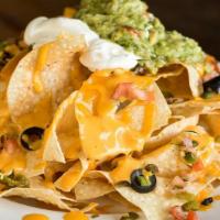 Hole In One Nachos · housemade tortilla chips with cheddar cheese, nacho sauce, pico, jalapenos, black olives; ga...