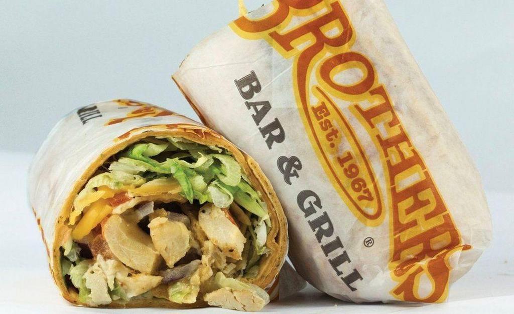 Queso Chicken Wrap · Grilled chicken, our famous queso sauce, with a blend of cheese, lettuce, fried corn tortilla chips, red onion and diced tomato in a tomato-basil flour tortilla wrap.
