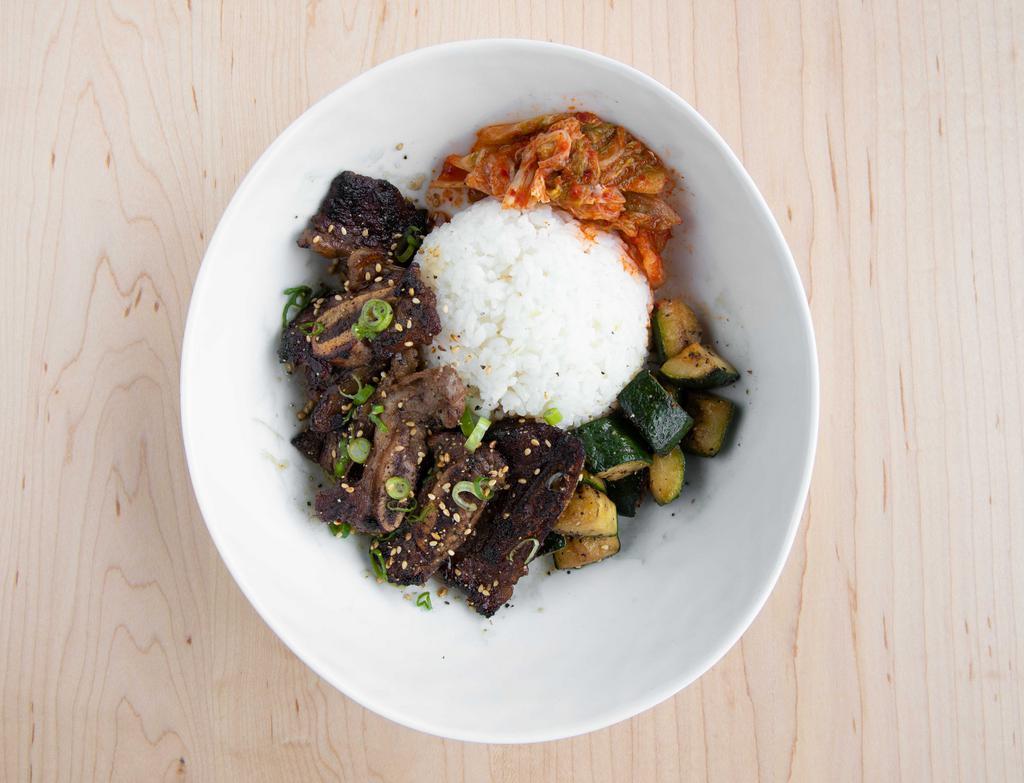 Galbi · Korean beef short ribs. Marinated Korean beef short ribs, scallion, roasted sesame, sautéed zucchini, kimchi, rice.