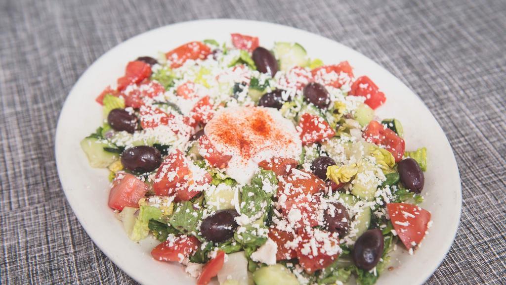 Greek Salad · A traditional Greek classic made with romaine lettuce, tomatoes, cucumbers, onions, kalamata olives topped with Feta cheese and our in-house dressing and tzatziki sauce.
