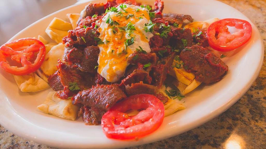 Iskender Plate · Beef and lamb gyro mixed with tomato sauce, layered with soft pita bread pieces, and covered with a healthy serving of tzatziki sauce.