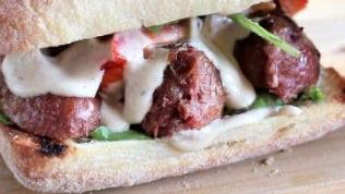 Vegan Sausage Sandwich · Vegan sausage with caramelized onions and grilled sweet peppers on a toasted bun.