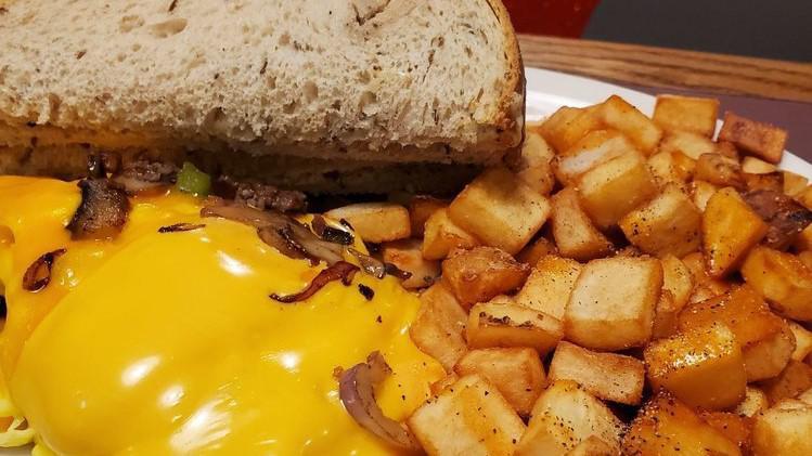 Steak Bomblette · Our classic omelette bursting with shaved steak, sautéed onions, peppers and mushrooms finished with American and cheddar cheese. served with hash browns