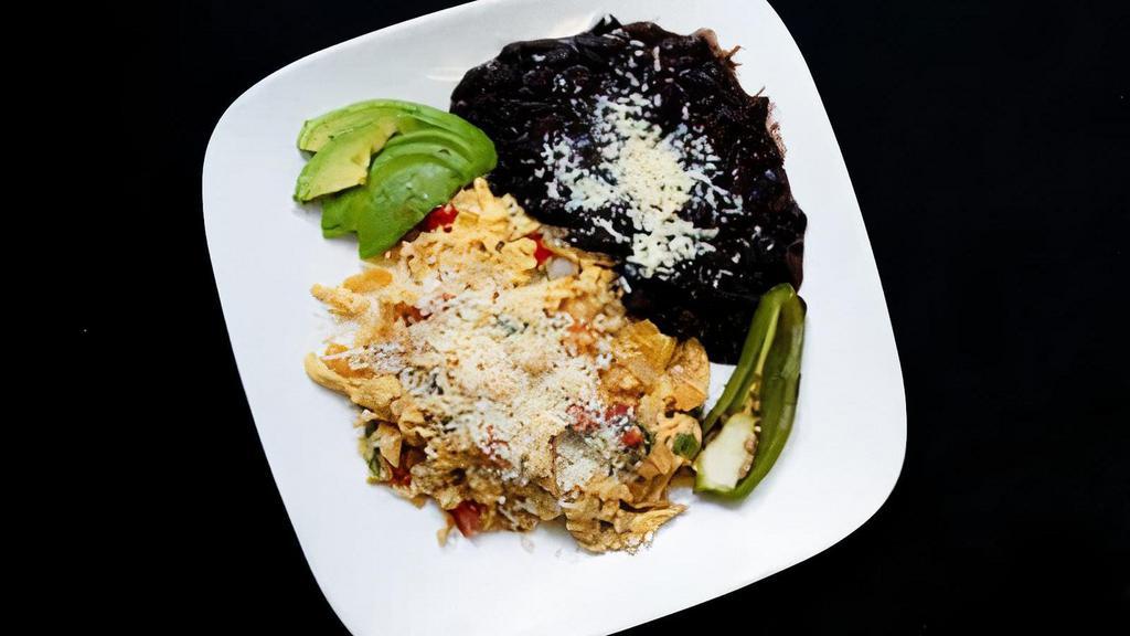 Migas · Scramble of eggs, tomatoes, corn tortilla strips, peppers, onions, cotija, served with black beans and avocado.