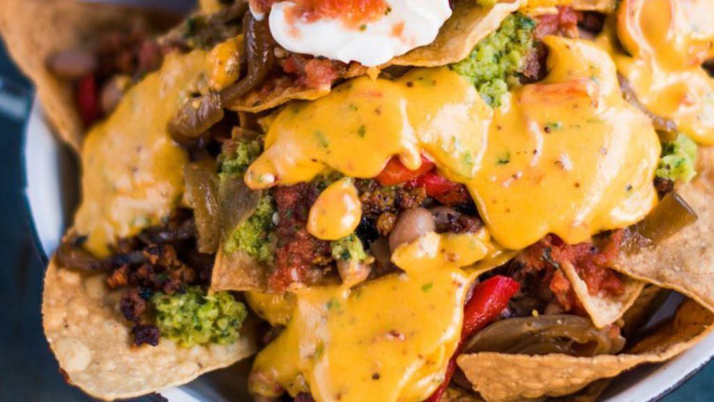 Nachos · Tortilla chips covered in nacho cheese and topped with ground beef, pinto beans, tomatoes, onions, sour cream, cotija cheese, and jalapeños.