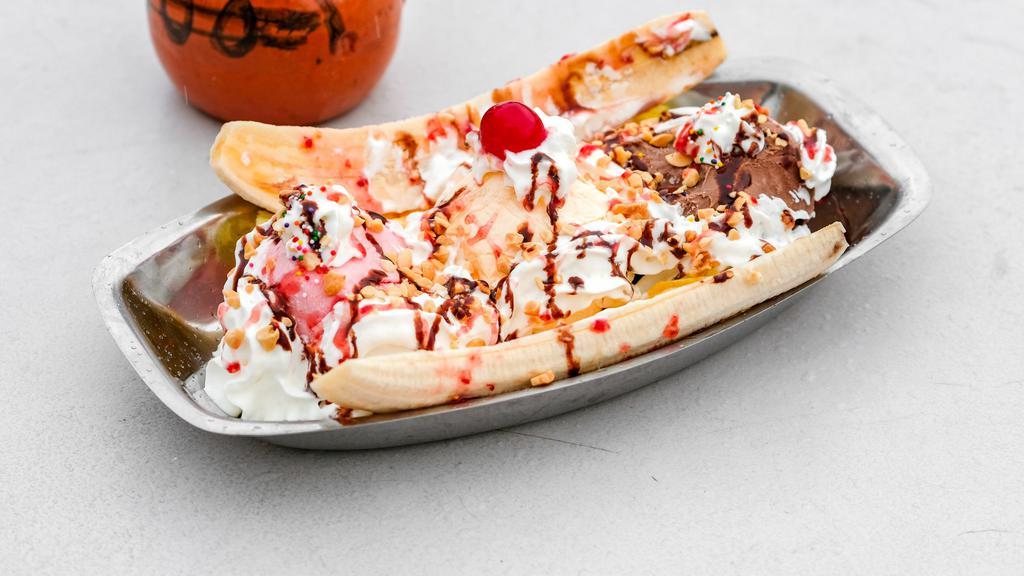 Banana Split · 2 banana slices served with 3 ice cream scoops and topped with whip cream, strawberry, chocolate, and crushed peanuts.