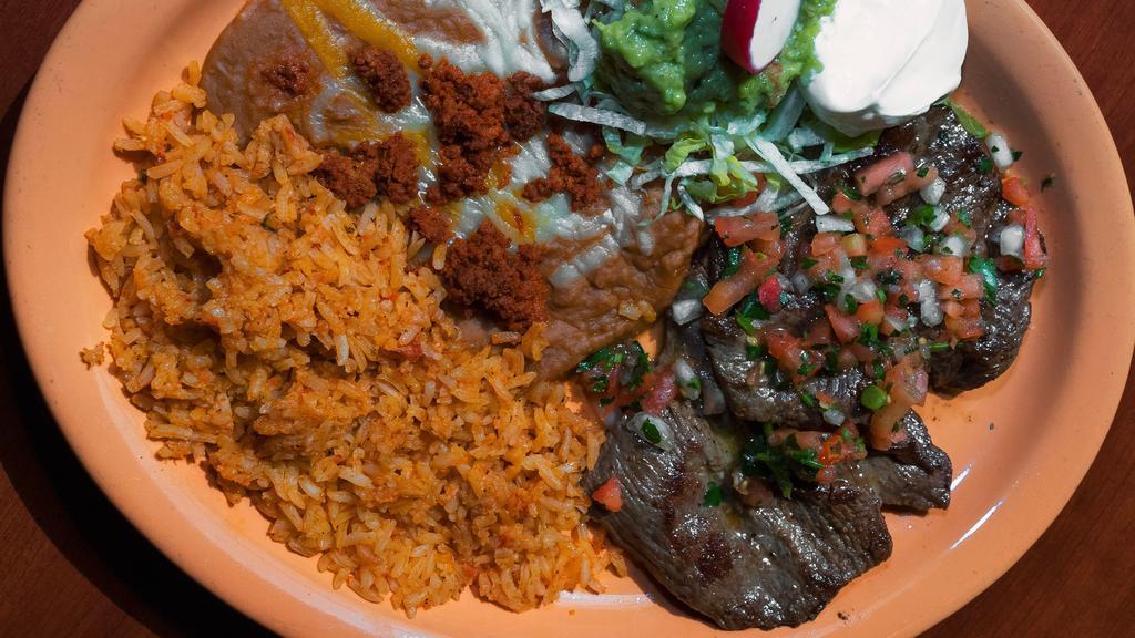 Carne Asada Angelina · A top quality cut of carne asada steak, grilled to tender perfection and served with chorizo topped refried beans, Spanish rice, fresh made guacamole, sour cream and home made tortillas.