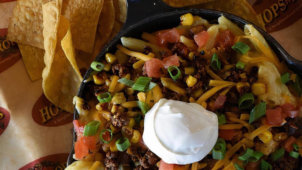 Fiesta Mac · A South of the Border Twist on an American classic. A blend of cheddar, pepper Jack, and Parmesan cheeses combined with taco meat and jalapeños. All topped with baja veggies, diced tomatoes & a scoop of sour cream. Served with tortilla chips.