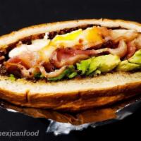 Breakfast Torta · Two slices of bread filled with ham, bacon, two fried eggs, avocado, and cheese.
