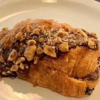 Chocolate Hazelnut Croissant · Twice baked croissant with an hazelnut cream filling and topped with chocolate and hazelnuts.