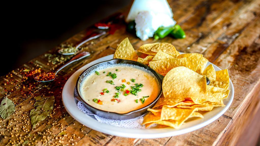 Queso Dip · Gluten-free. Tasty and creamy pepper jack cheese dip, flavored with poblano peppers. Served hot with our crispy homemade tortilla chips.