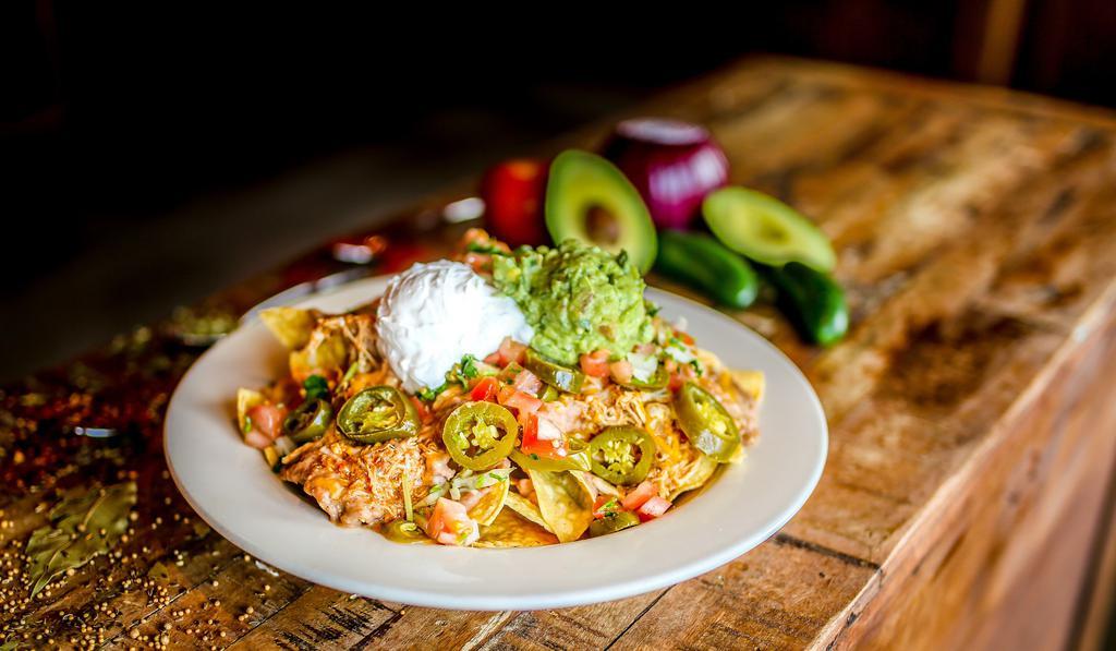 Nachos · Gluten-free. Refried beans, mixed shredded cheese, lettuce, sliced pickled jalapeño peppers, sour cream, tomatoes, and guacamole. All piled high on corn tortilla chips. + Choice of bean and cheese, shredded chicken, shredded beef, ground beef, or grilled chicken.