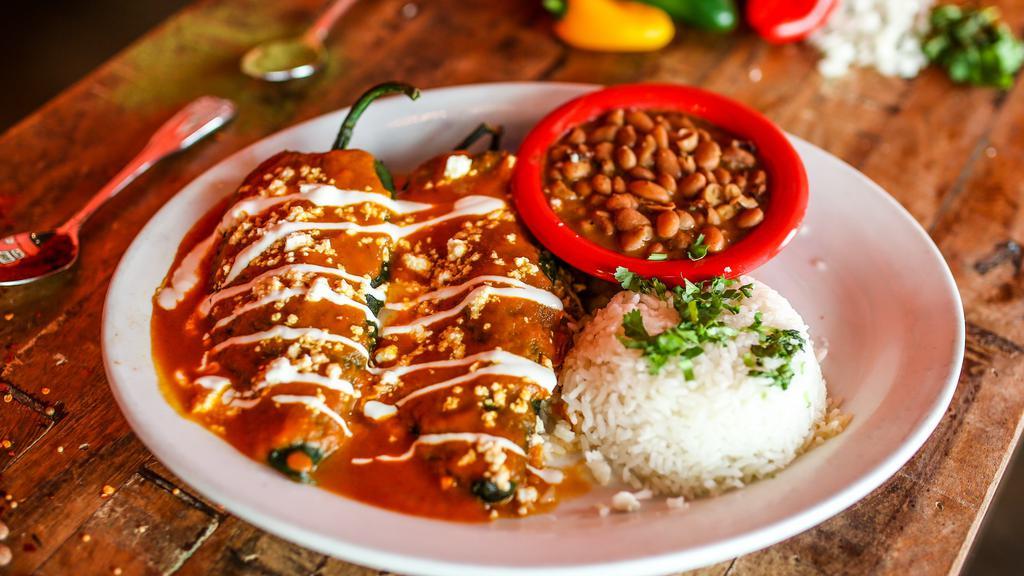 Dos Poblanos · Gluten-free. Mild poblano chiles stuffed with Jack cheese, shredded chicken, smothered with red sauce and sprinkled with queso fresco. Served with Mexican rice, charro beans and drizzled with Mexican cream.