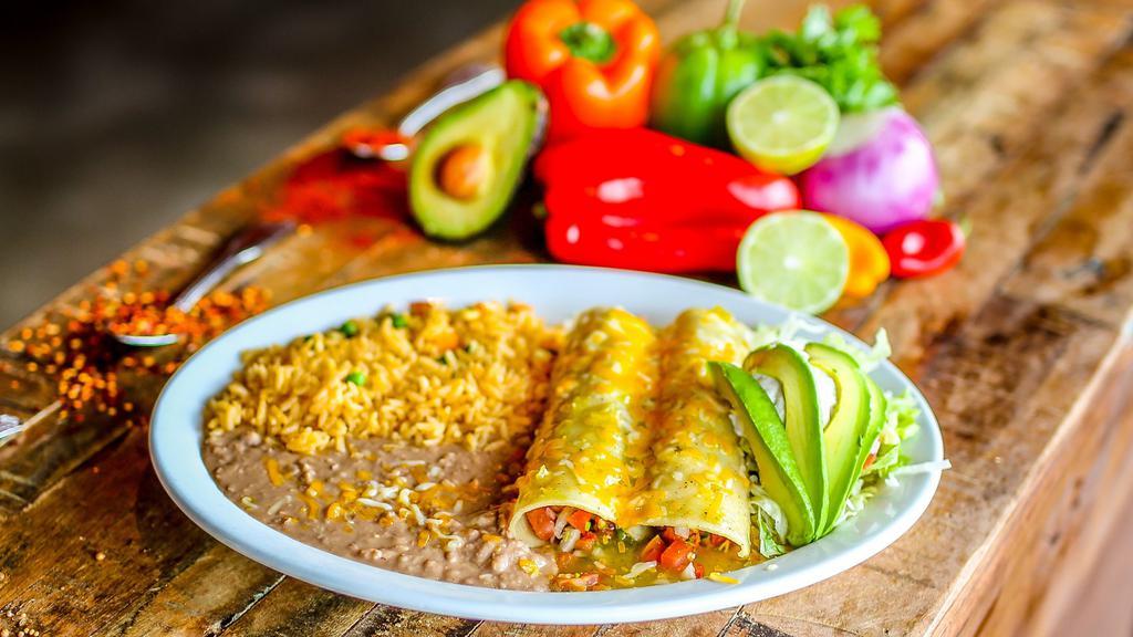 Enchiladas De Camarón · Gluten-free. A pair of enchiladas stuffed with succulent shrimp sautéed in with tomatoes, onions, and cilantro; topped with queso dip, lettuce, tomatoes, and avocado slices. Served with Mexican rice and refried beans.
