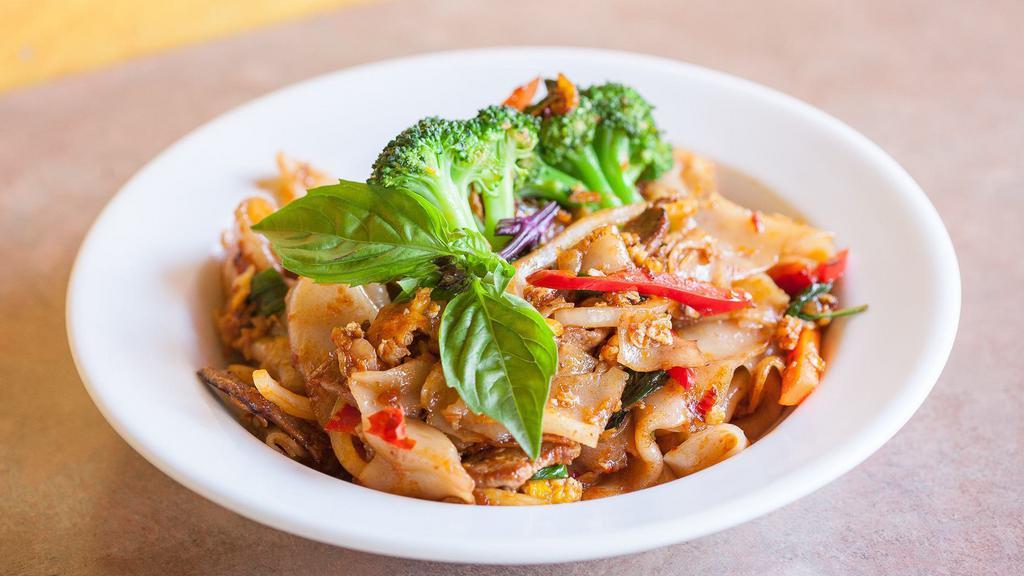 Pad Kee Mow (Chili Noodles) · Stir-fried wide-flat rice noodles with egg, onion, bell pepper, basil leaves, broccoli, carrots, and chili sauce.