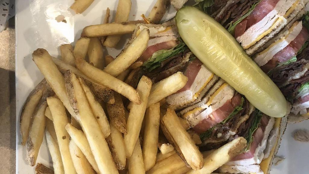 Turkey Triple Decker Sandwich · Three slices of white toast with smoked turkey, bacon, lettuce, American cheese, tomato, mayo, and a pickle on the side. All of our sandwiches are served with French fries and a pickle.