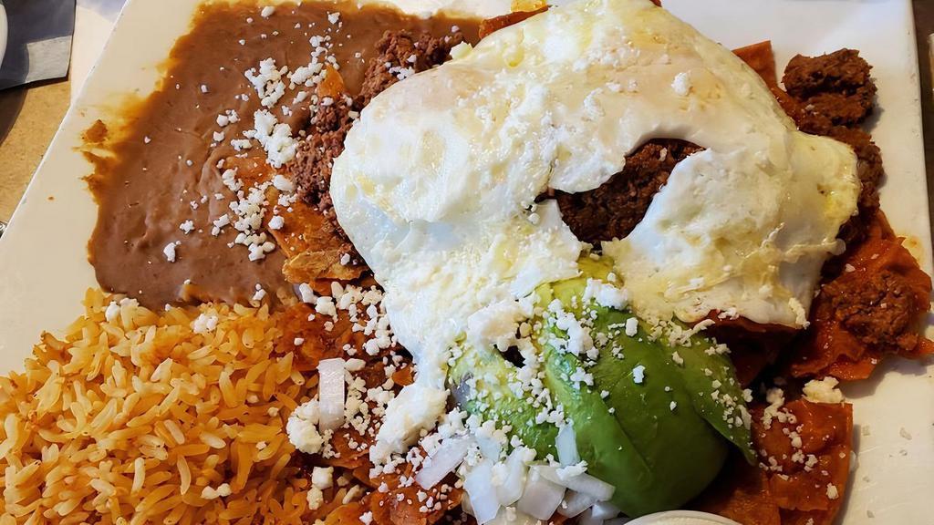 Chilaquiles · Corn tortillas simmered in a spicy tomato salsa topped with diced onion, queso fresco, sliced avocado served with two eggs your way, rice, refried beans and sour cream on the side.