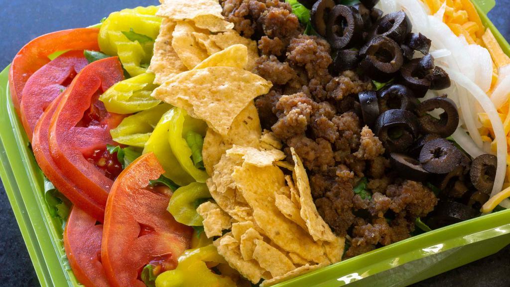 Beef Taco Salad · Iceberg Lettuce, taco seasoned beef, Cheddar cheese, raw onions, taco chips, tomatoes, mild peppers and black olives.